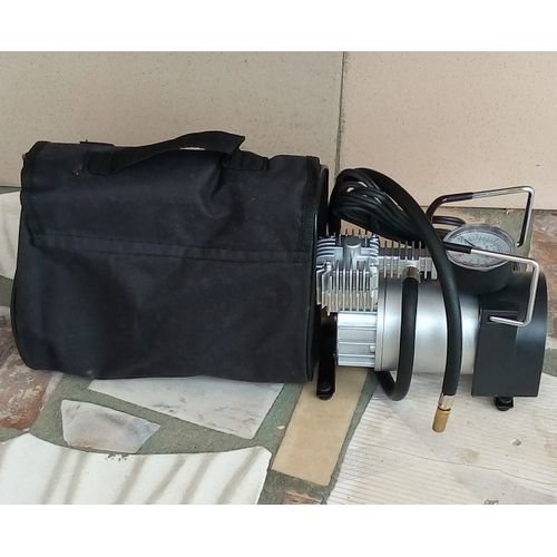 12 V portable metal tire inflator air compressor with gauge and hose on white background.